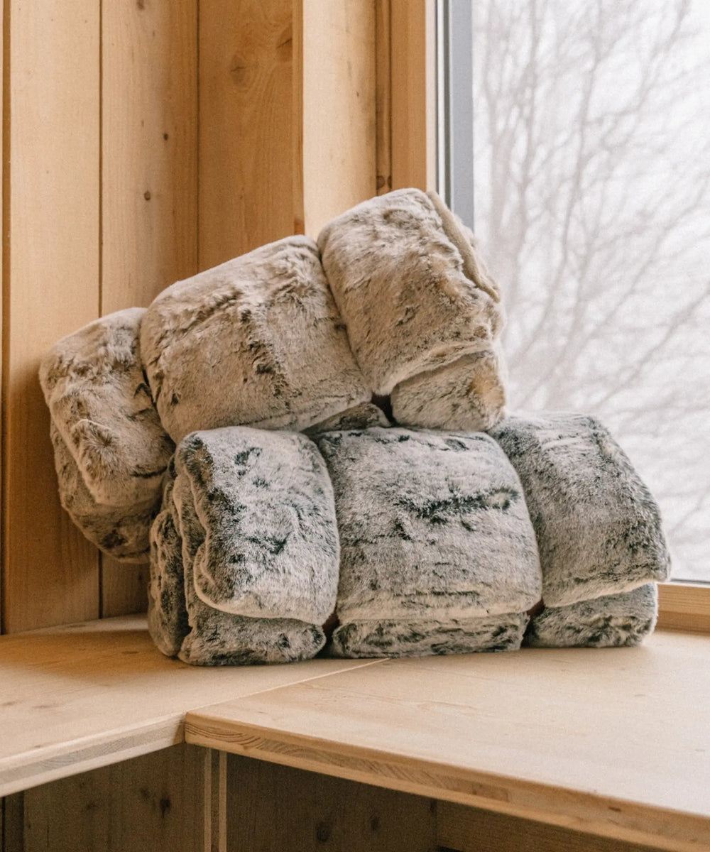 Plaid fausse fourrure Frisson sombre gris WARO empilé en ambiance chalet