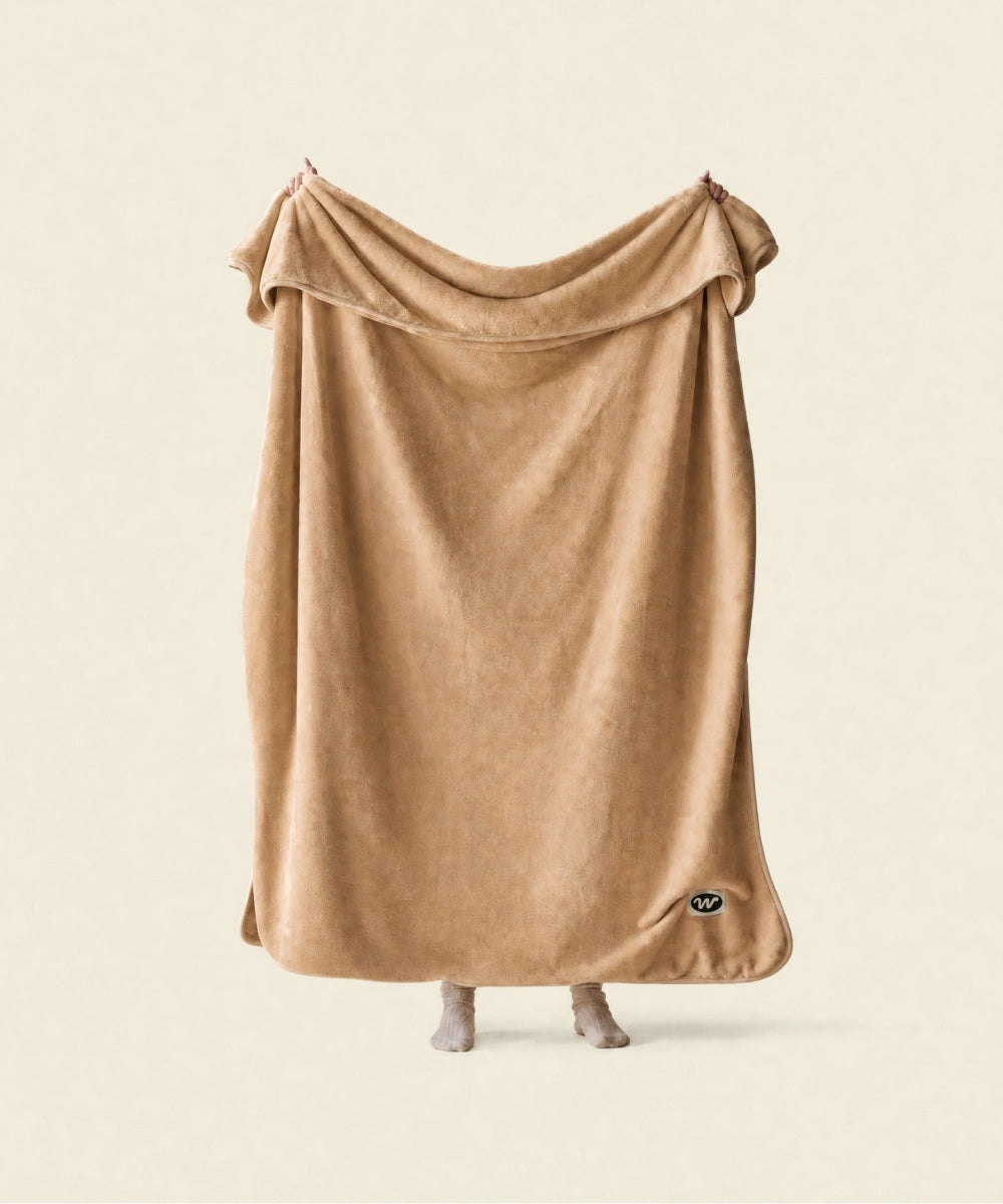 Plaid polaire cosy nougat waro tendu par une personne sur un fond beige