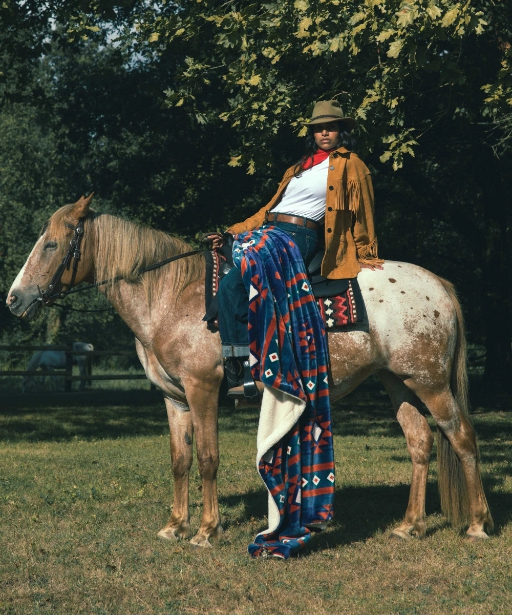 Wurf blaue Navajos auf den Knien einer Frau auf einem Pferd