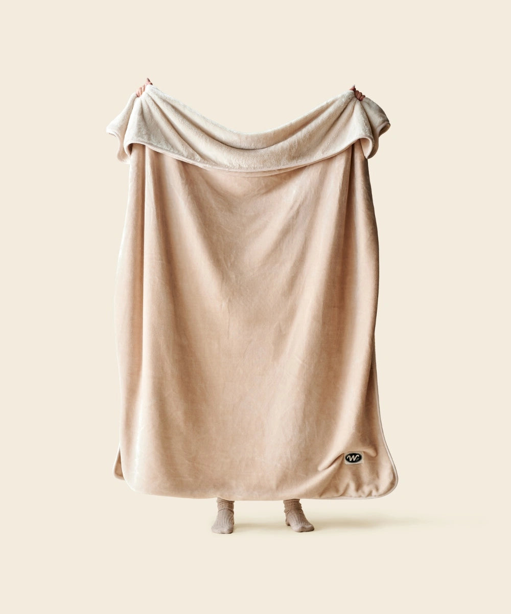 Plaid polaire cosy beige waro tendu par une personne