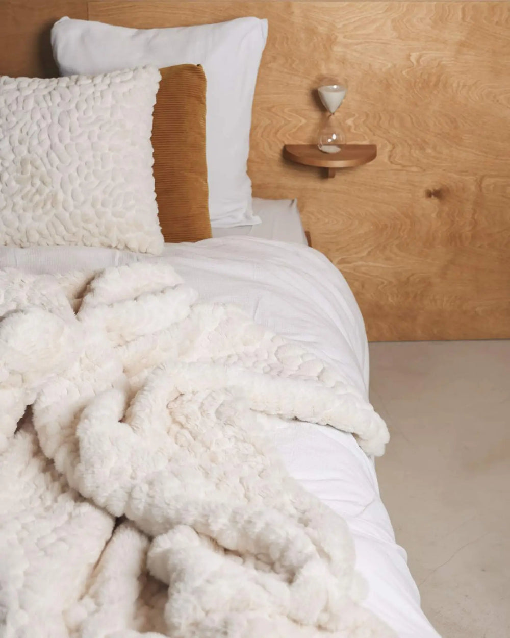 Couvre-lit en fausse fourrure galet waro disposé sur un lit blanc
