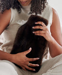 Bouillotte cocon fourrure marron waro dans les mains d’une femme