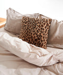 Coussin fourrure léopard  waro posé dans un lit 