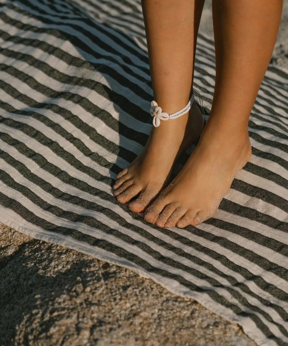 Détail de la fouta rayée grise WARO en coton doux, utilisée comme serviette de plage.