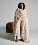 Plaid fausse fourrure waro beige posé sur un lit blanc 