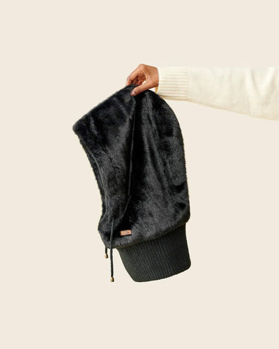 Cagoule  fourrure noire  waro tenue par une main sur fond beige.