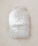 Bouillotte galet fourrure waro posé à plat sur un fond beige 