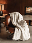 Plaid ours polaire waro blanc posé sur un fauteuil marron 