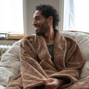 Peignoir hôtel fausse fourrure camel WARO porté par un homme assis