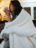 Personne savourant une boisson chaude enveloppée dans le Plaid Maxi Berbère WARO