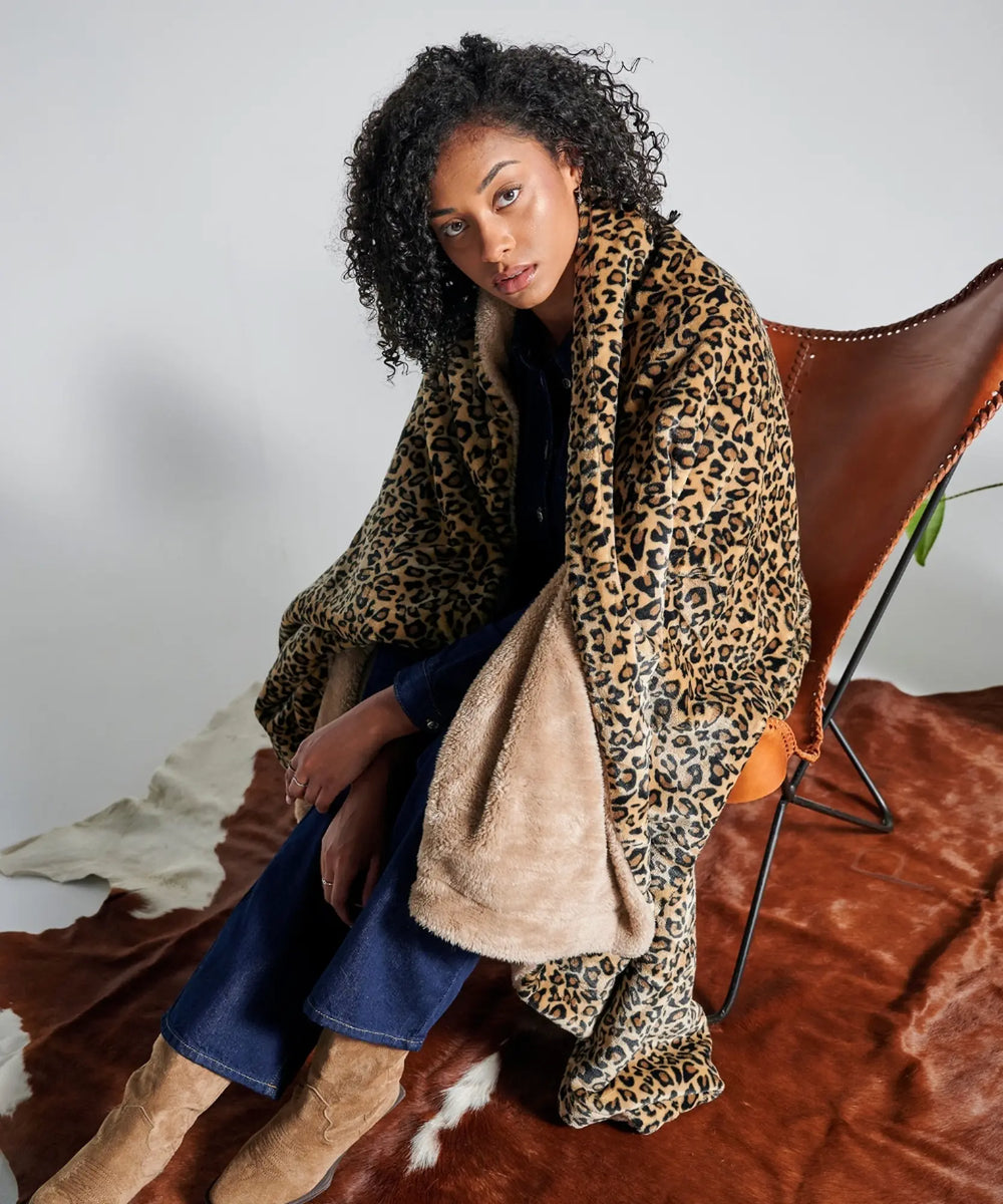 Modèle assis enveloppé dans le plaid Wild Léopard WARO sur une peau décorative
