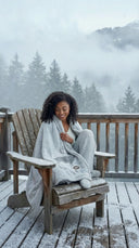 Plaid polaire cerf gris enroulé autours d’une femme dans un chalet