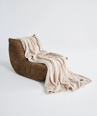 Plaid polaire waro beige posé sur un togo taupe 