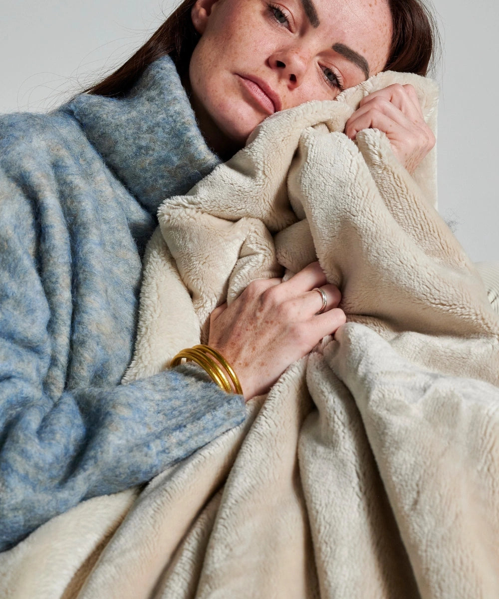 Plaid polaire cosy beige waro tenu dans les mains d’une femme