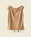Plaid polaire cosy nougat waro tendu par une personne sur un fond beige