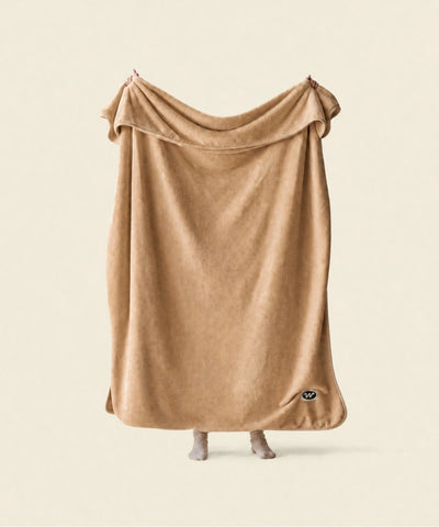 Plaid polaire cosy nougat waro tendu par une personne sur un fond beige