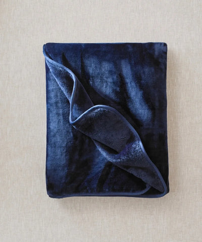 Plaid cosy bleu nuit polaire waro posé à plat sur un fond beige 