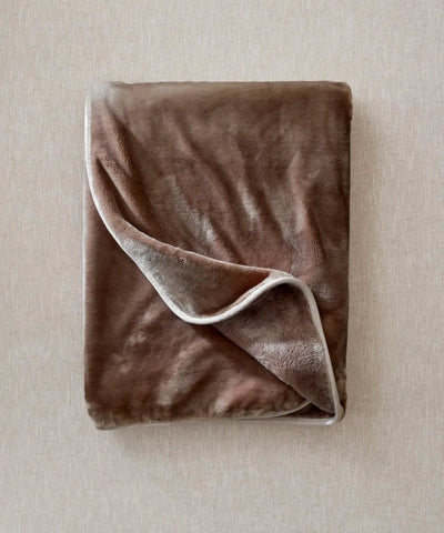 Plaid polaire cosy taupe waro posé à plat sur un fond beige 