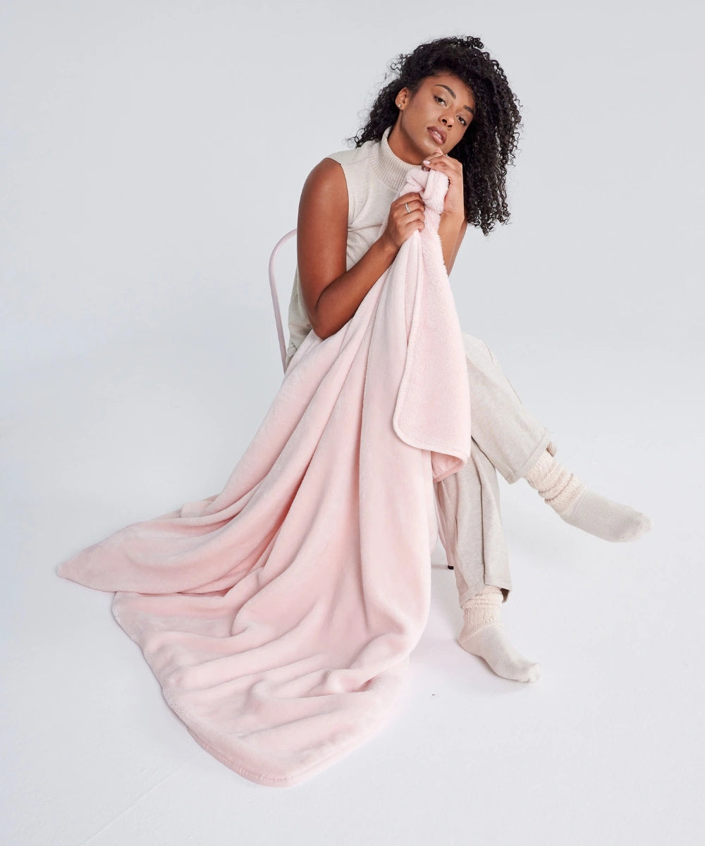Cosy waro powder pink fleece blanket held in a woman's hands