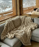 Plaid fausse fourrure dune waro posé sur un canapé dans un chalet