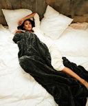 Plaid fausse fourrure waro gris posé sur une femme allongé sur un lit