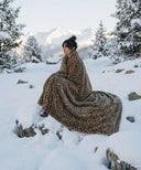 Plaid polaire leopard waro enroulé autours d’une femme à la neige