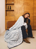 Plaid polaire rbleu waro posé sur une femme assise sur un fauteuil