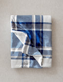 Plaid polaire tartan bleu posé à plat sur un fond beige