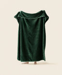 Plaid polaire cosy vert cypres waro tendu par une personne sur un fond beige