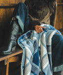 Plaid polaire tartan bleu tenu par une femme sur un banc 