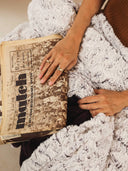 Ondes Sauvages textured purple fleece blanket, placed on the lap for a cosy reading moment.
