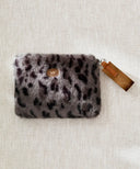 Pochette fourrure leopard gris waro posé à plat sur un fond beige