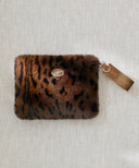 Pochette fourrure leopard marron waro posé à plat sur un fond beige