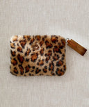 Pochette fourrure leopard premium posé à plat sur un fond beige
