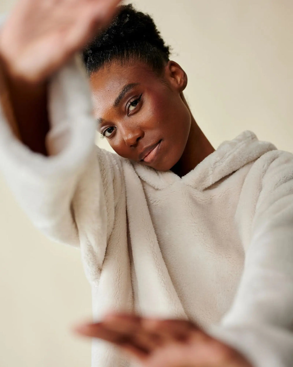 Model wearing WARO cream Chill Teddy plaid sweater, soft teddy material, close-up view of face and hood.