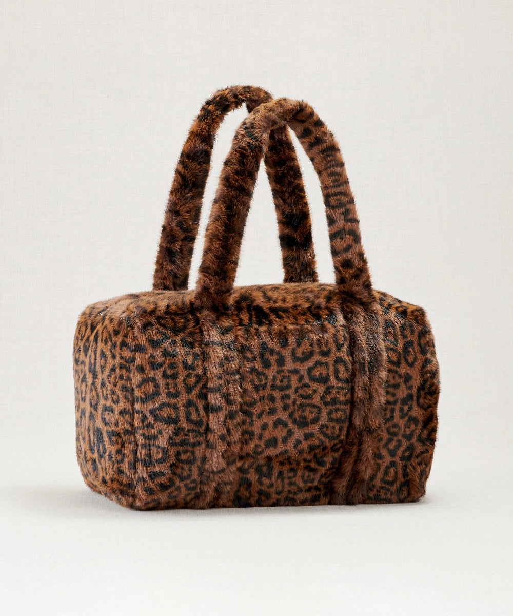 Sac weekender fausse fourrure waro posé sur un fond beige 