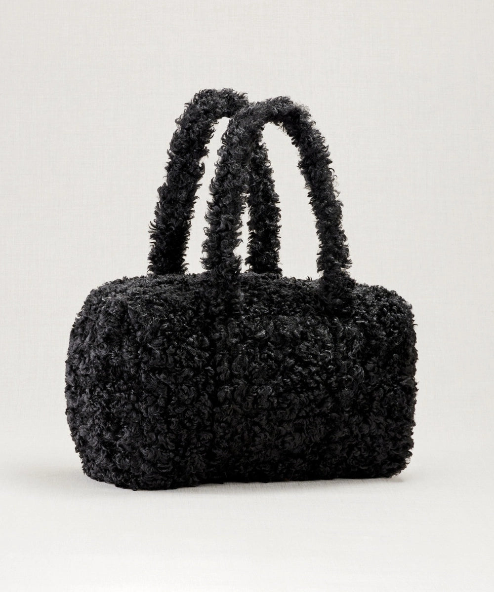 Sac weekendermotif teddy noir waro posé sur un fond beige 