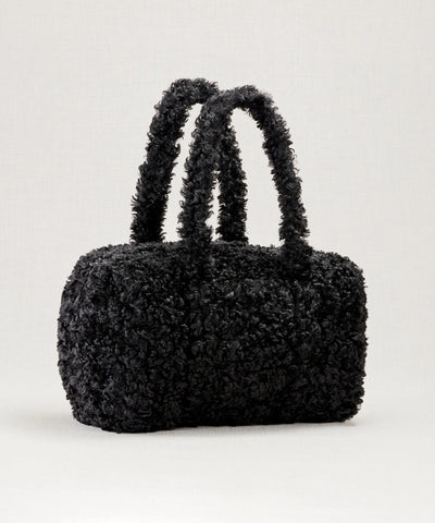 Sac weekendermotif teddy noir waro posé sur un fond beige 