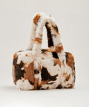 Sac fausse fourrure motif vache waro posé sur un fond beige