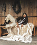 Plaid fausse fourrure waro beige sur un banc avec une femme posé au dessus