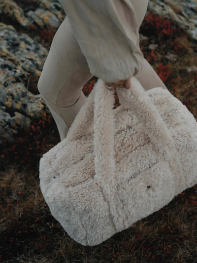 Gros plan sur une femme tenant un sac weekender en bouclette beige waro