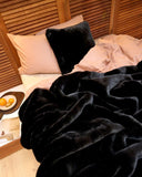 Coussin WARO en fausse fourrure panthère noire sur un lit élégant.