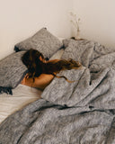 Dessus de lit en coton indigo WARO installé sur un lit, mettant en valeur la couleur profonde et le tombé naturel du textile.