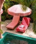 fouta rayee rose rouge posee sur un bain de soleil
