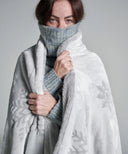 Plaid polaire gris à motifs flocons de neige waro enroulé autours d'une femme