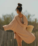 Poncho en gaze de coton café WARO porté en extérieur, idéal pour la plage ou les moments détente.