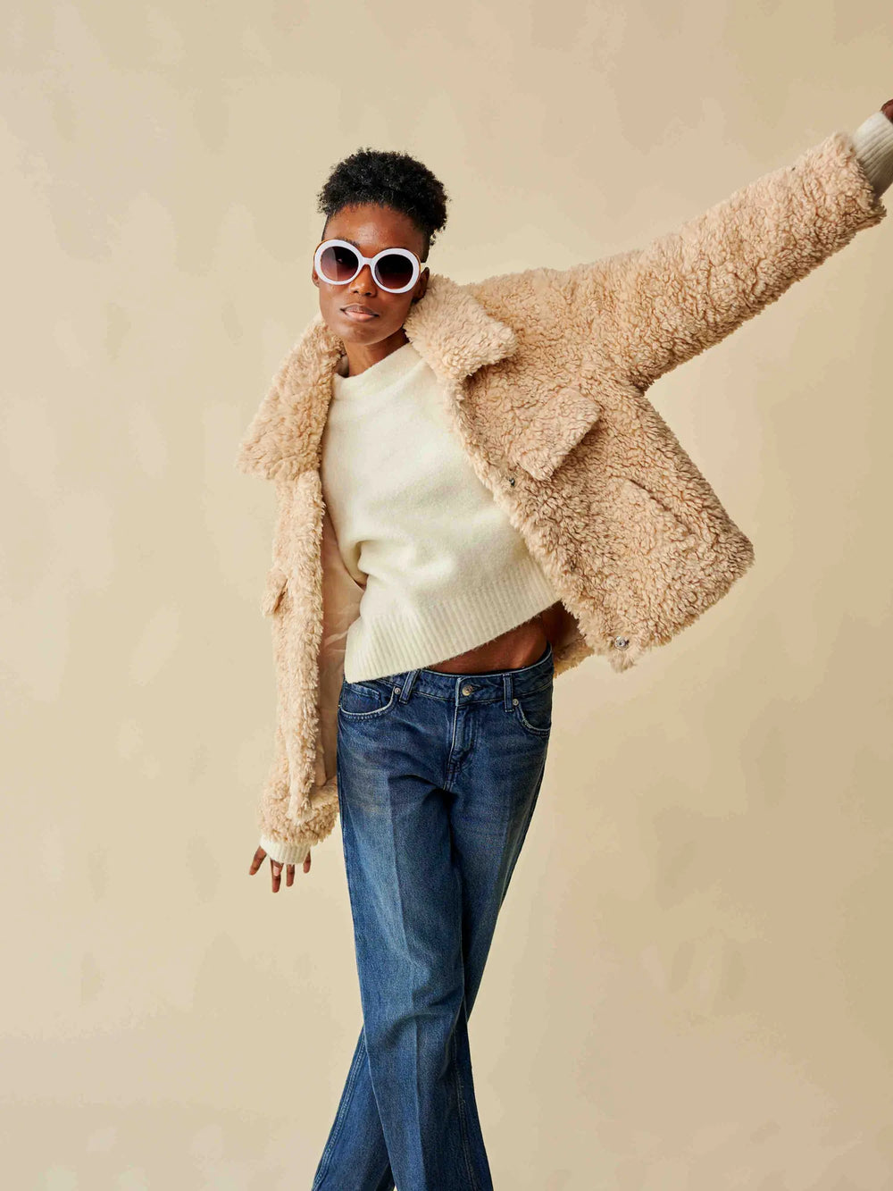 Veste courte teddy bear beige en moumoute portée avec jean en studio.
