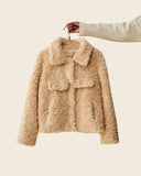 Veste courte teddy bear beige en moumoute présentée sur cintre.