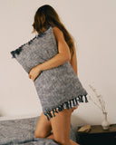 Coussin en coton indigo WARO porté par une personne, texture souple et franges visibles