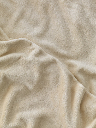 Zoom sur la texture douce du plaid polaire Yoga beige WARO.